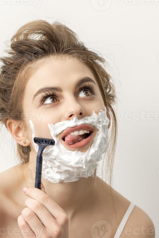 kvinna rakning ansikte med rakapparat foto
