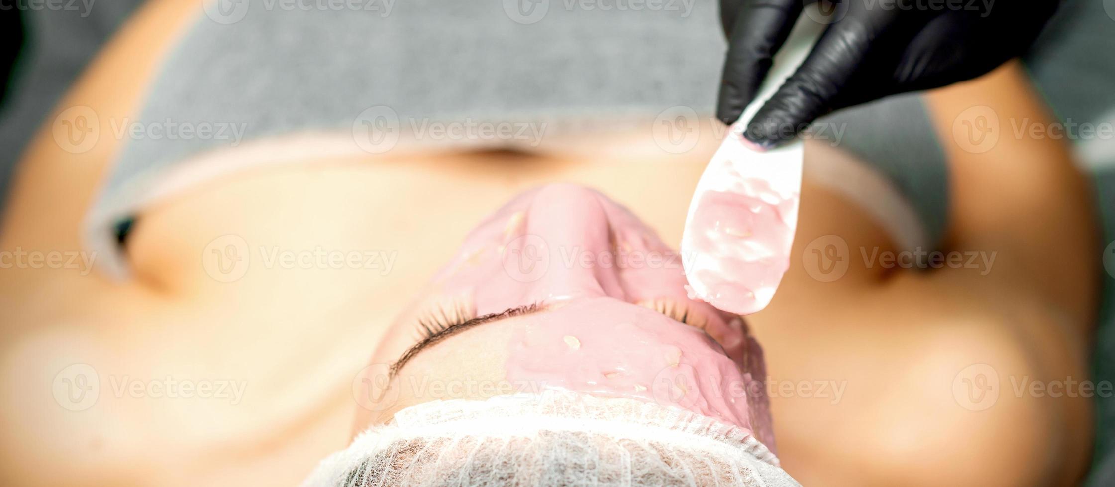 kosmetolog applicering ett alginisk mask foto