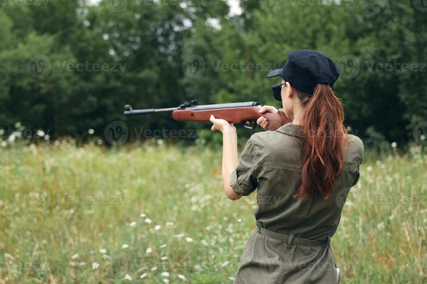 kvinna vapen siktar jakt mål bak- se vapen grön träd foto