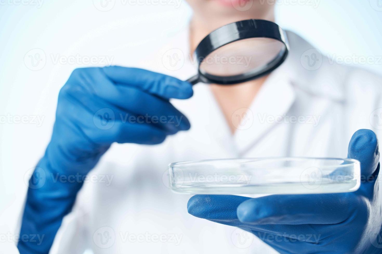 kvinna laboratorium assistent i en vit täcka ser genom en förstorande glas professionell forskning foto