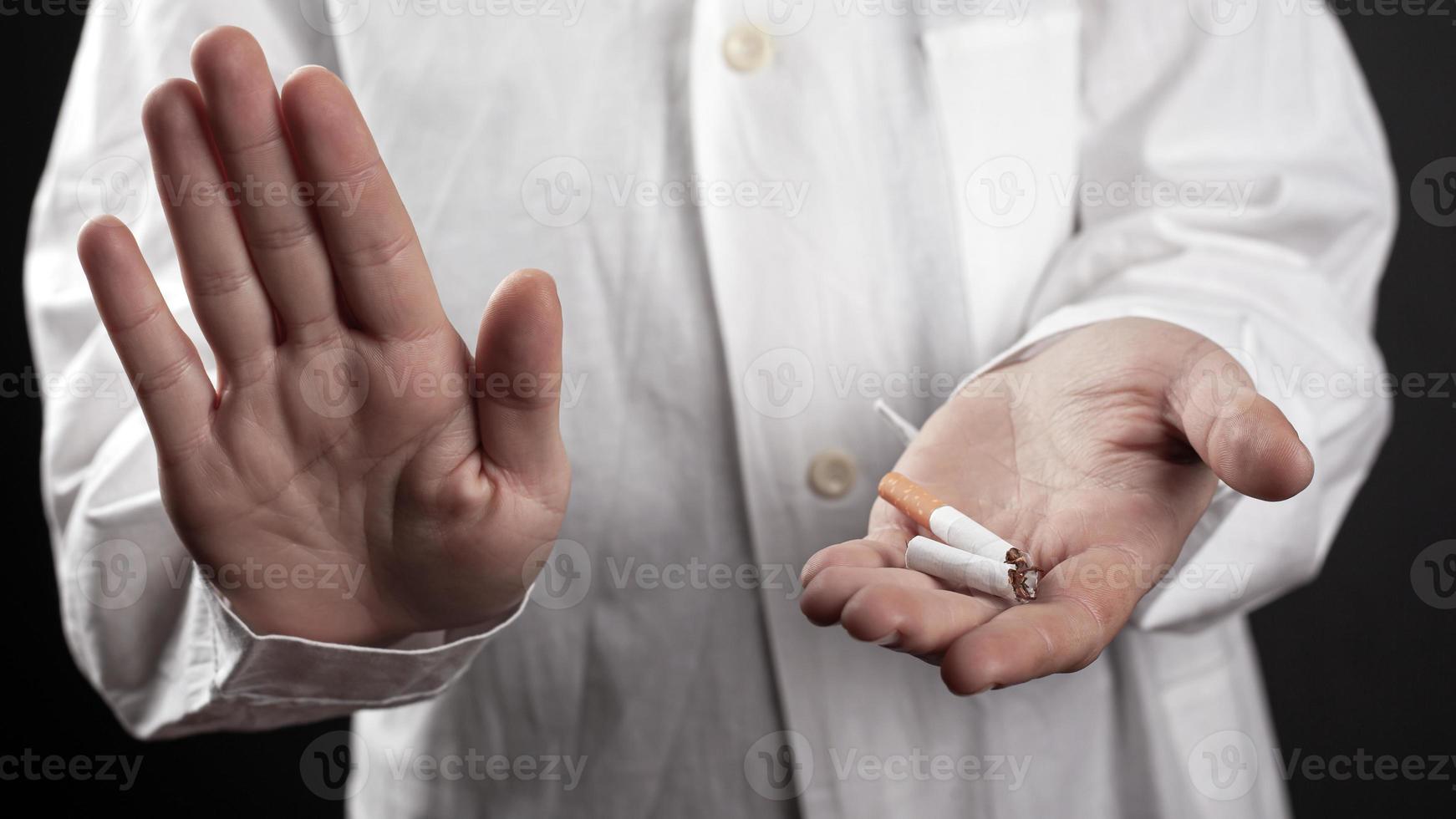 sluta röka koncept med en trasig cigarett i händerna på en läkare foto