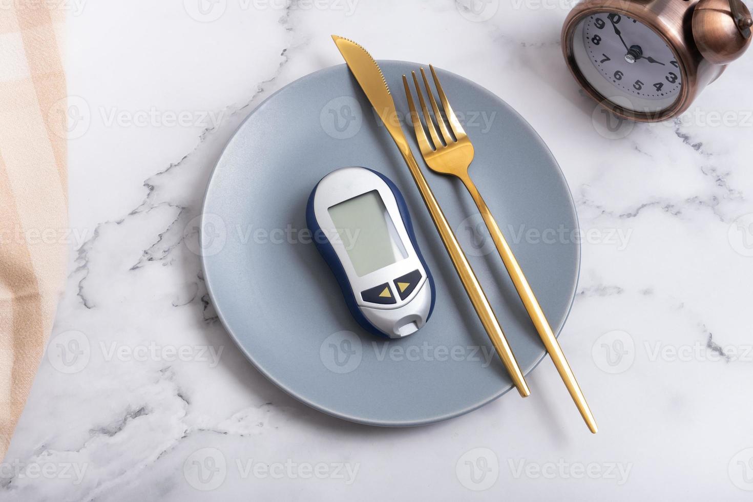 tallrik med glukometer och bestick på tallrik och larm klocka. diabetes diet begrepp foto