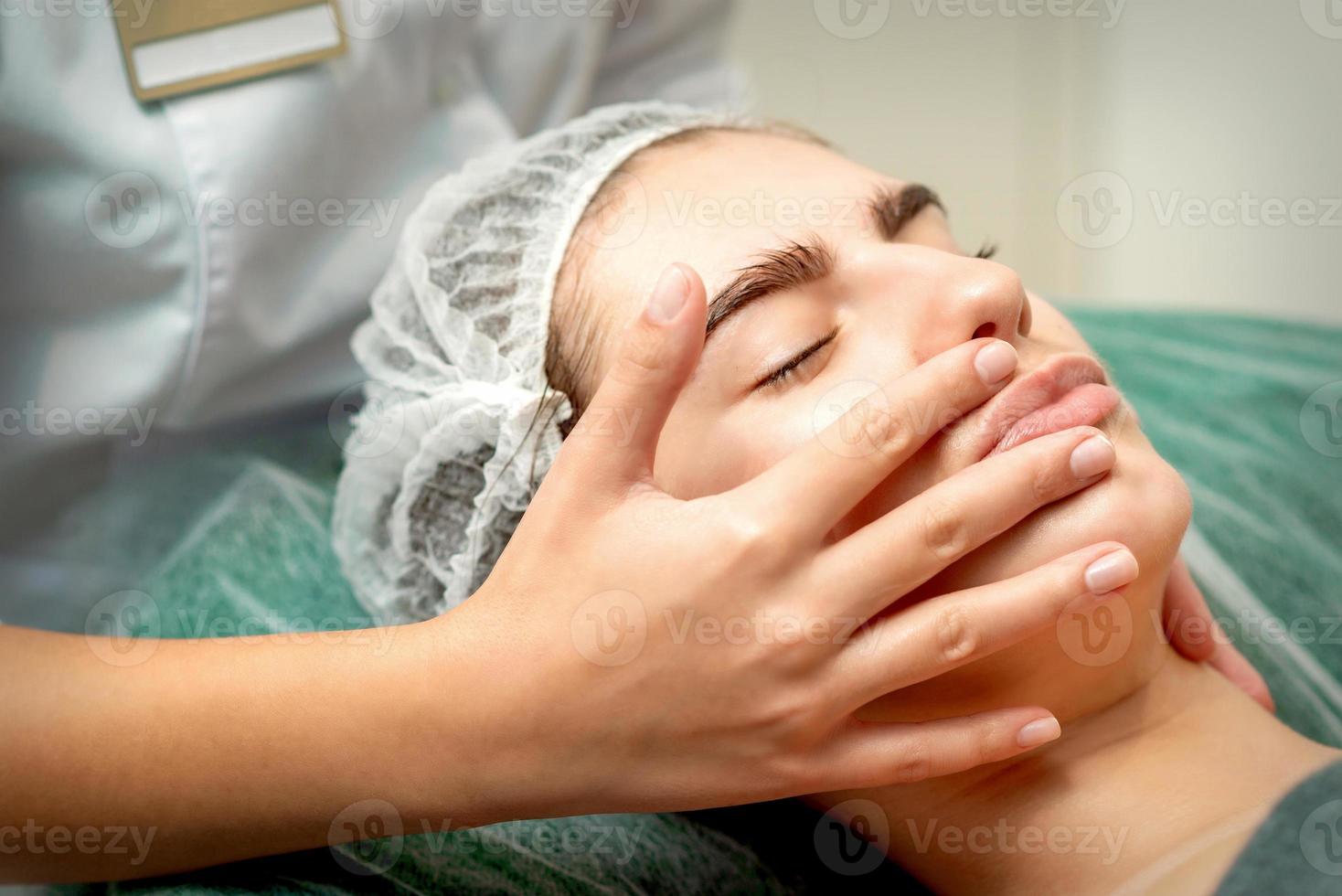 ung kvinna tar emot ansiktsbehandling massage foto