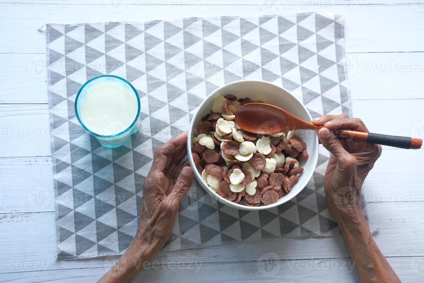 ovanifrån av äldre kvinnor som äter choklad majsflingor i en skål foto