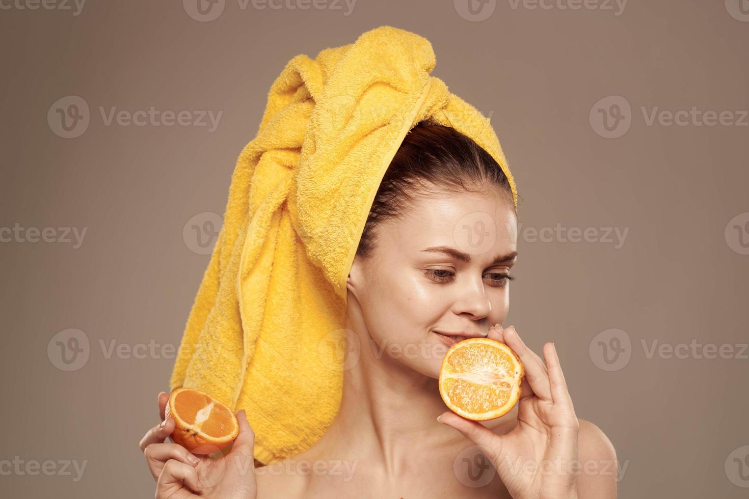 kvinna med en handduk på henne huvud bared axlar citrus- frukt i händer hud vård foto