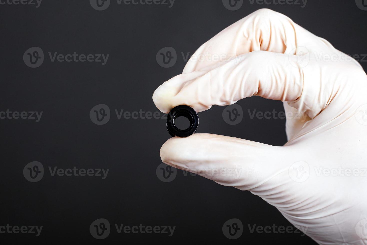 hand i en vit steril handske håller piercing tunnel i svart färg foto
