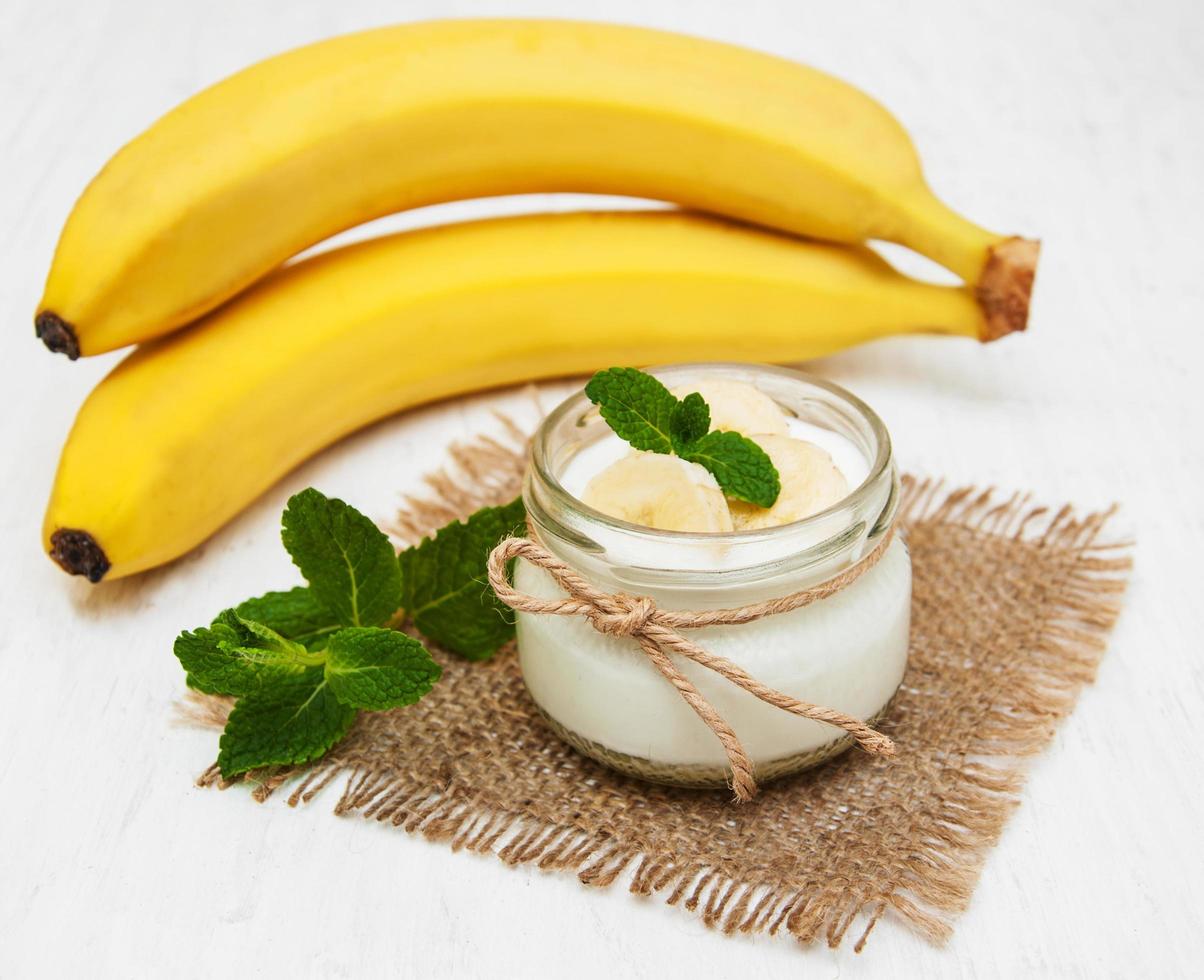 banan med naturlig yoghurt på en gammal vit träbakgrund foto