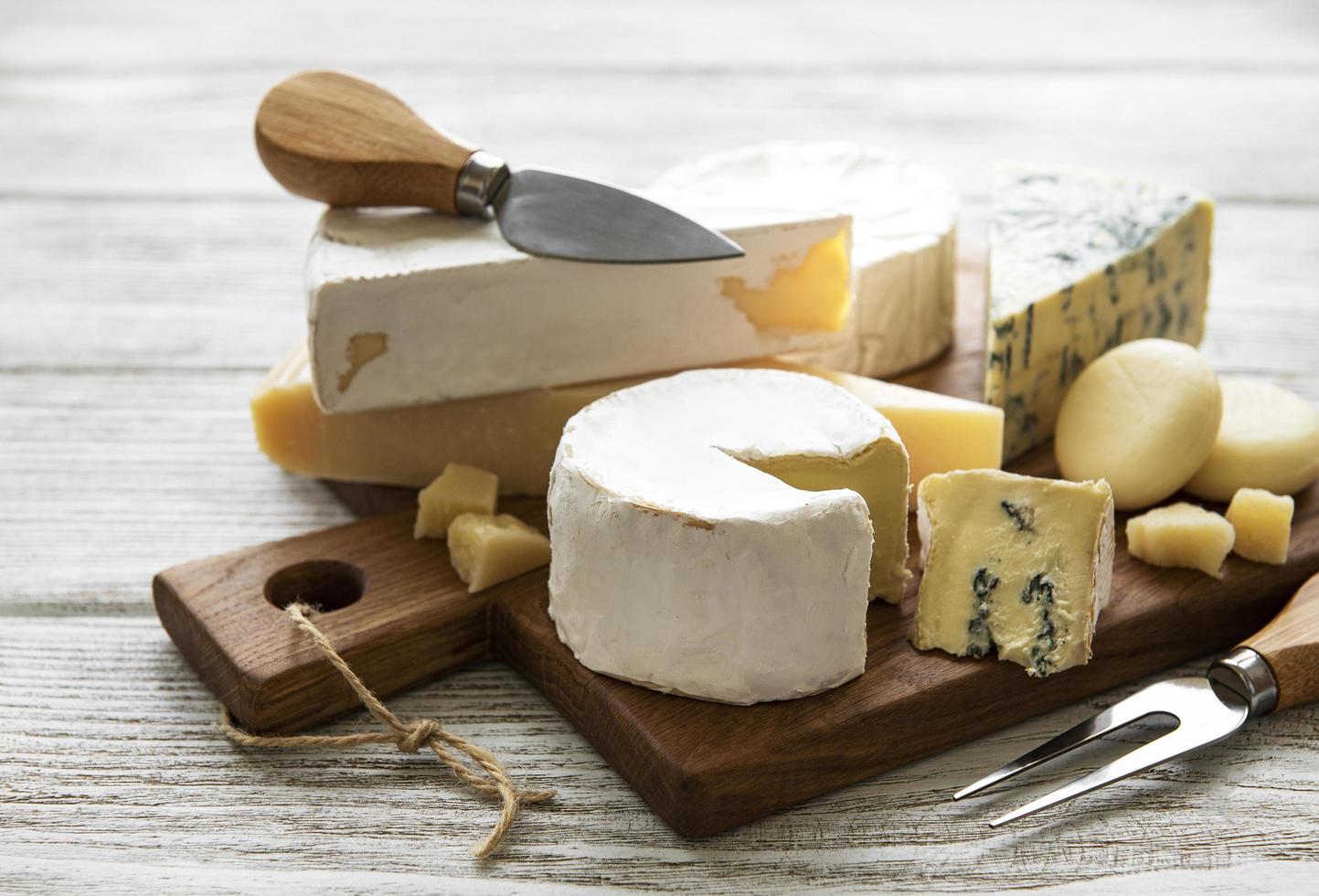 olika typer av ost på en vit trä bakgrund foto