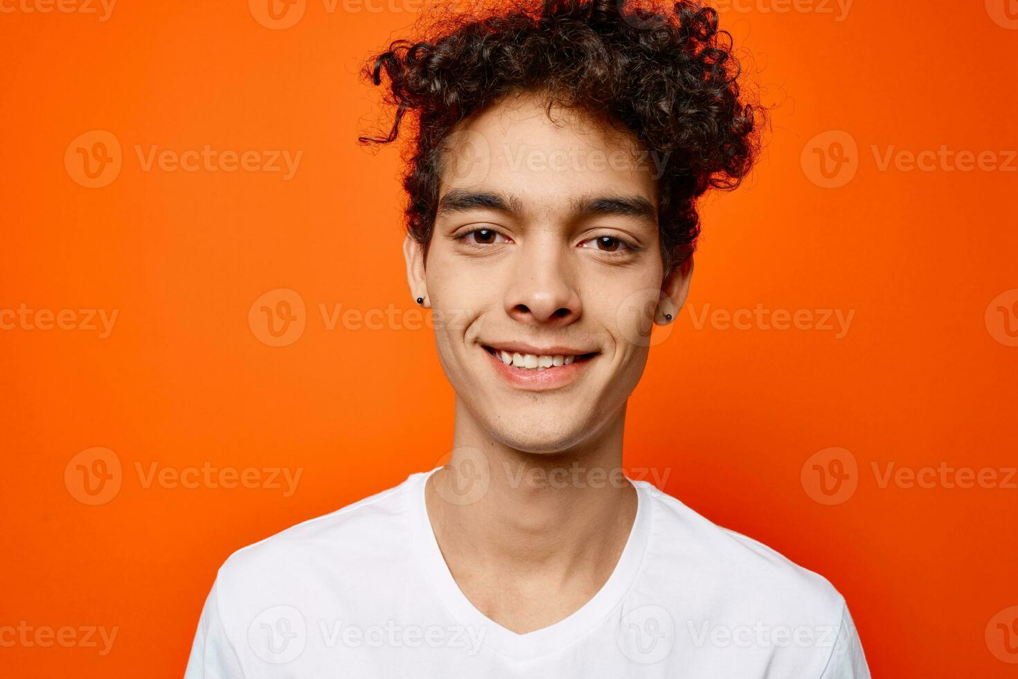 söt kille lockigt hår vit t-shirt modern stil orange bakgrund foto