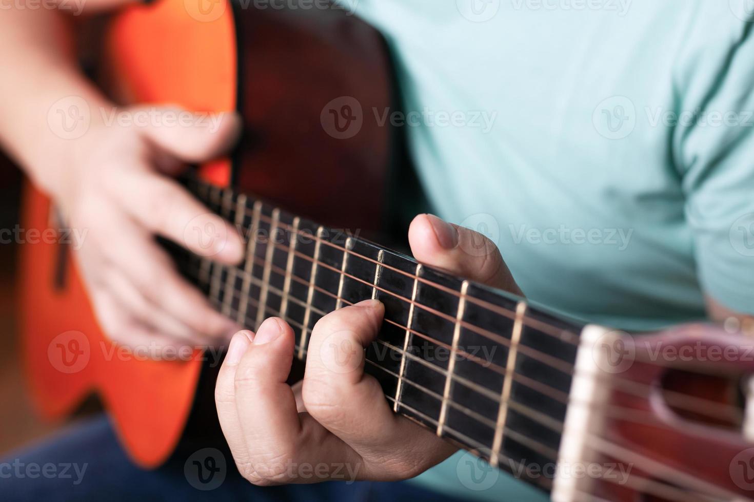 spelar akustisk gitarr närbild, hand griper ackordet, spelar ett musikinstrument foto