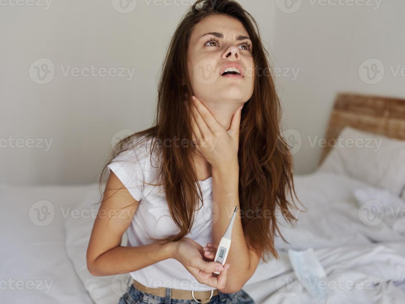 kvinna med en termometer i henne händer innehar de nacke upprörd feber foto