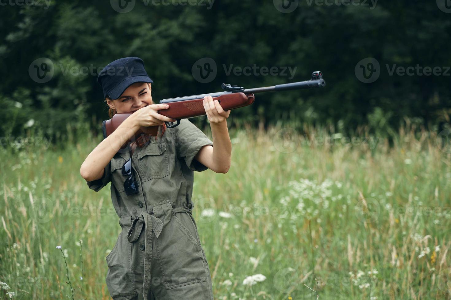 kvinna pistol i hand siktar jakt livsstil på utomhus- svart keps foto