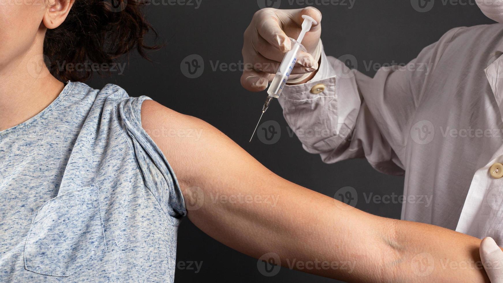 läkare ger en injektion till en sjuk patient på en mörk bakgrund foto