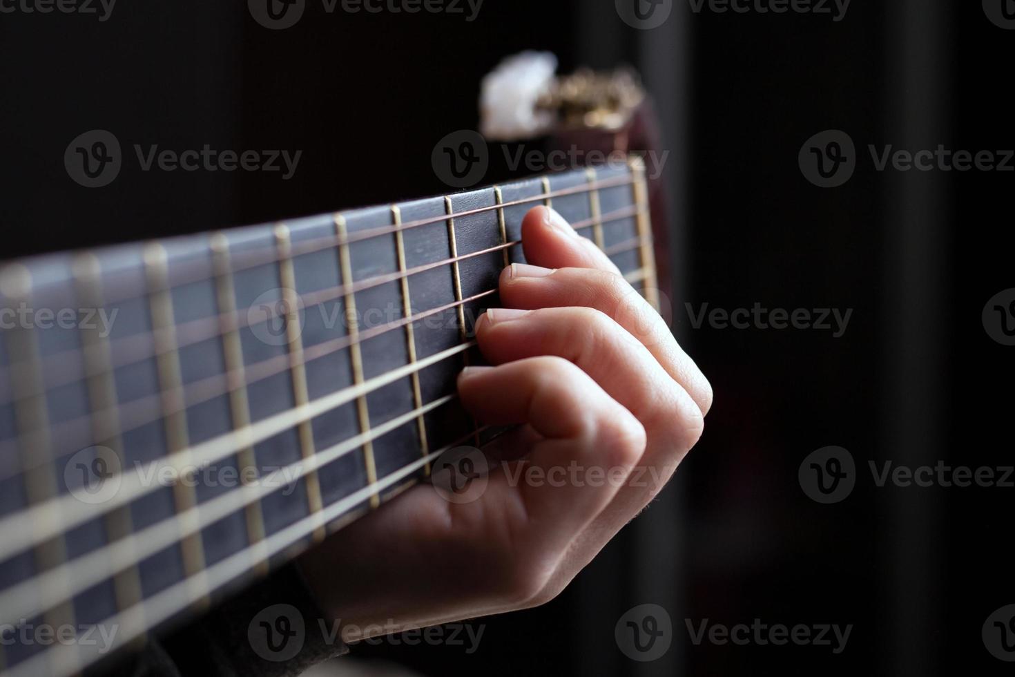 kvinnlig hand klämmer fast ett ackord på en akustisk gitarr foto