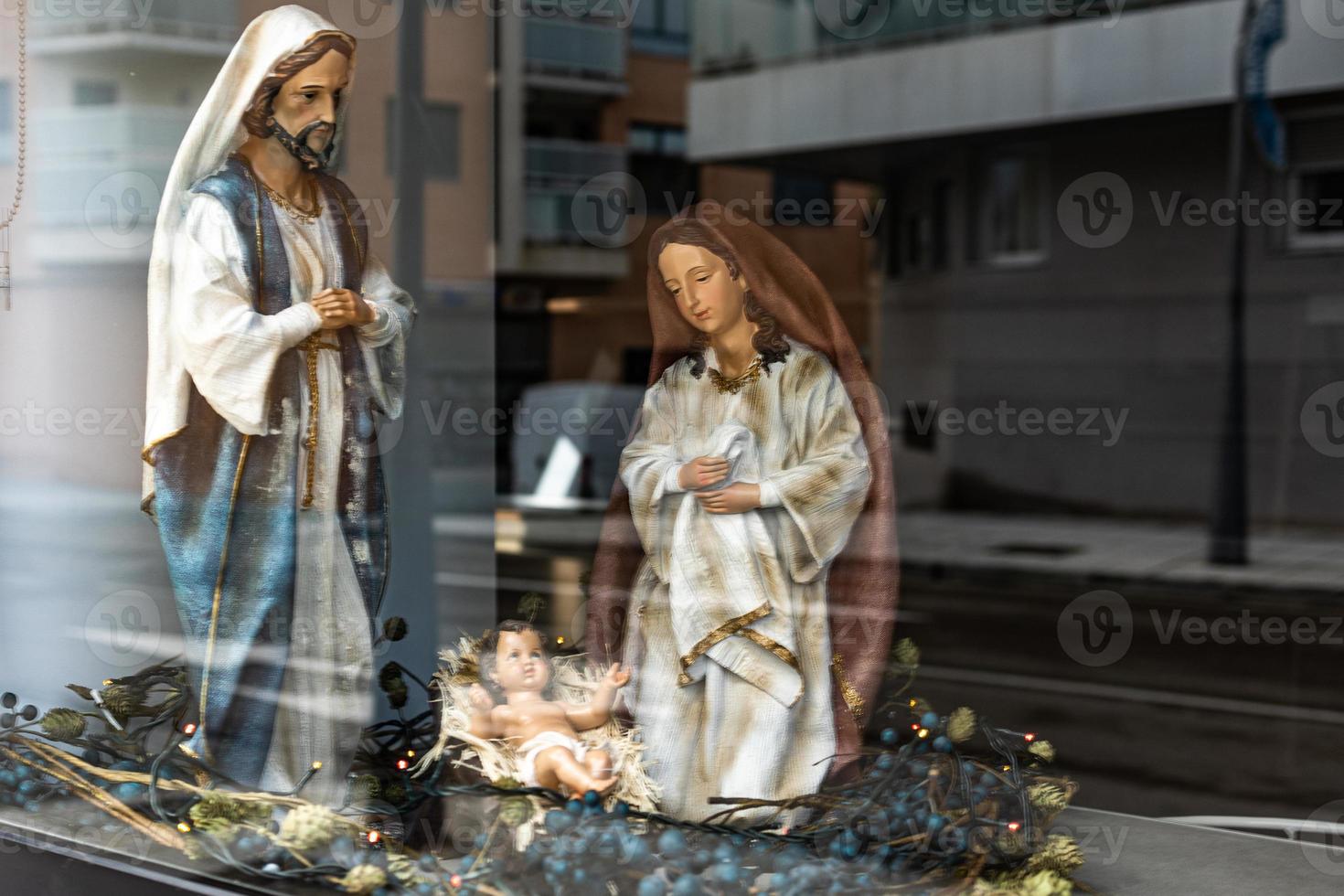 stor siffror av helgon från de nativity scen för jul, stänga till de reflexion av de stad i de glas foto