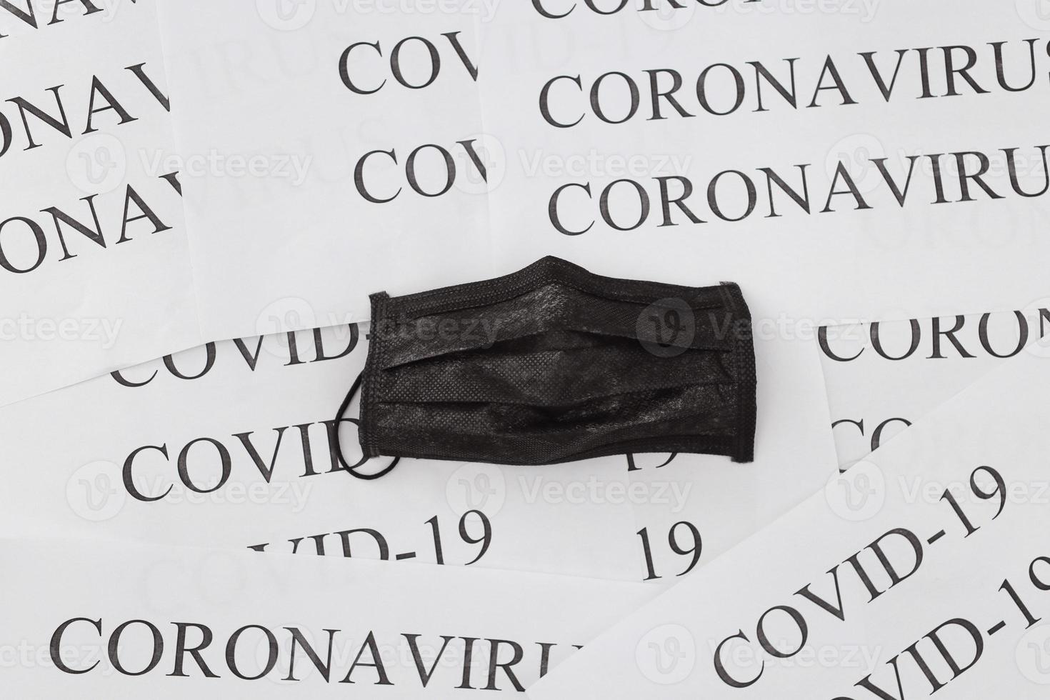 svart medicinsk mask på coronavirus inskriptioner bakgrund och covid-19. koncept för föroreningar, virus och influensa. professionell kirurgisk utrustning foto