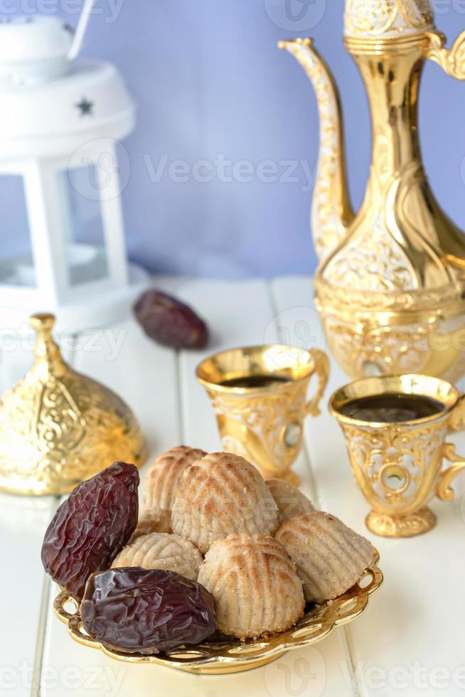 ramadankoncept. maamoul traditionell arabfylld bakelse eller kaka med dadlar eller nötter serveras med kaffe gyllene set. östra godis. närbild. vit trä bakgrund. foto