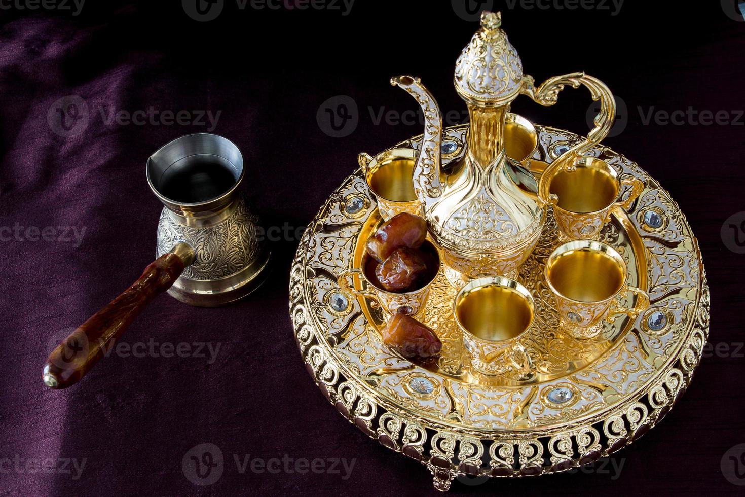 stilleben med traditionellt gyllene arabiskt kaffeset med dallah, kaffekanna och dadlar. mörk bakgrund. vertikalt foto