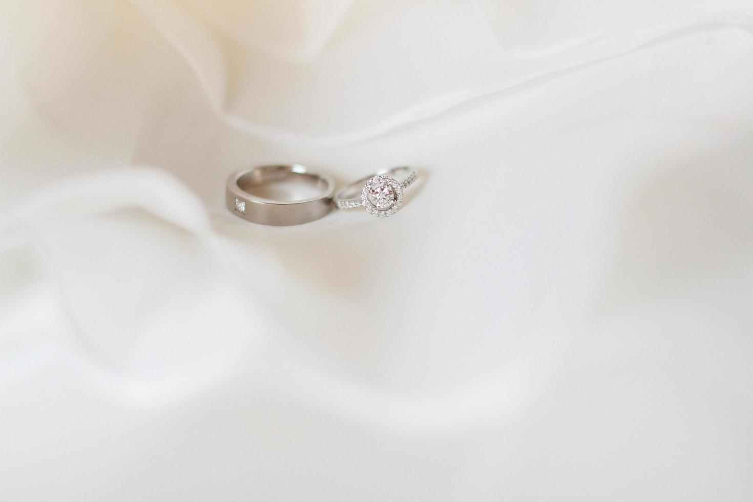 silver- och diamant ringar av brudgum och brud på en vit trasa i bröllop dag. valentines dag och kärlek för firande begrepp. foto