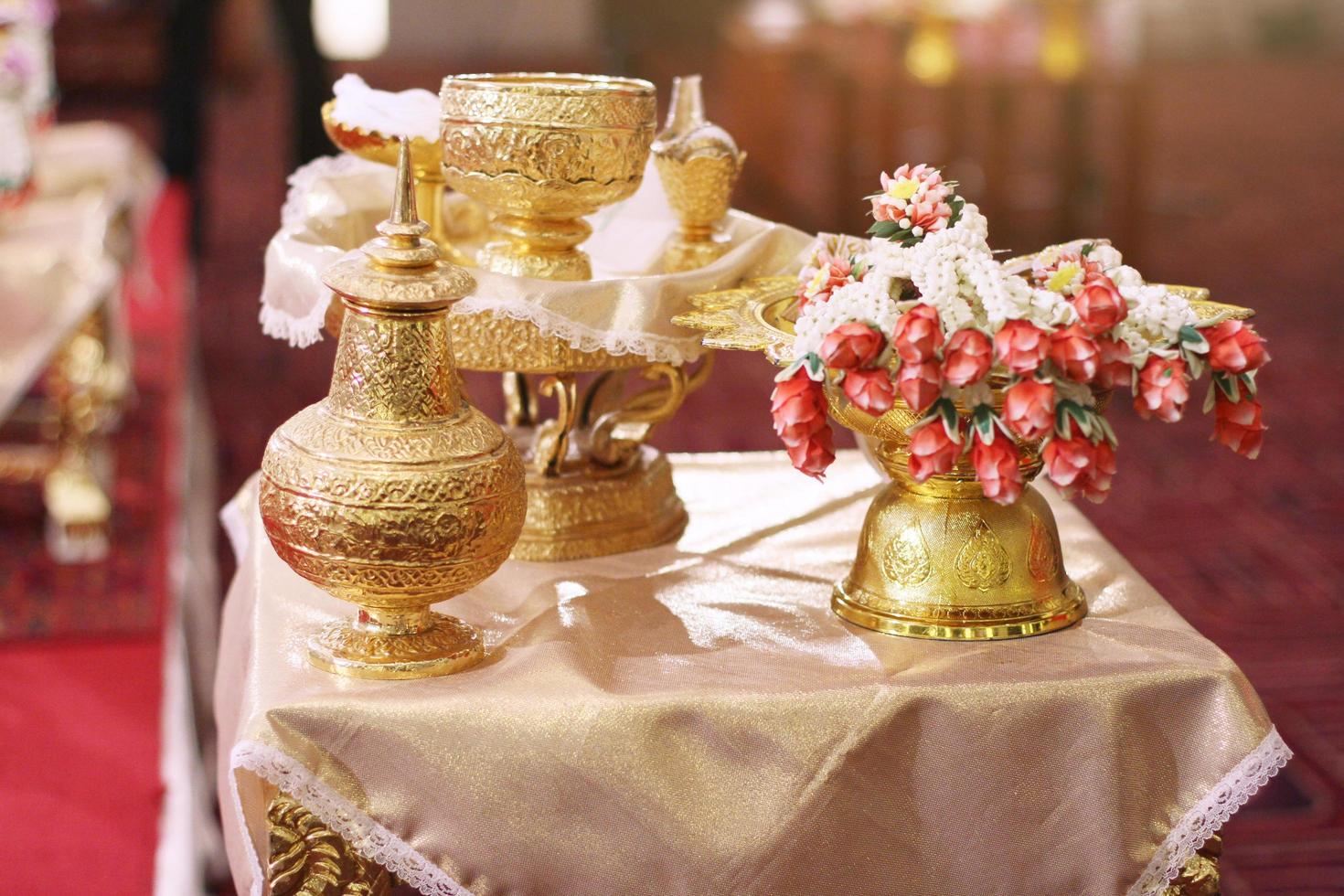 gyllene trumpetsnäcka uppsättning och blomma kransar för thai vatten häller bröllop ceremoni foto