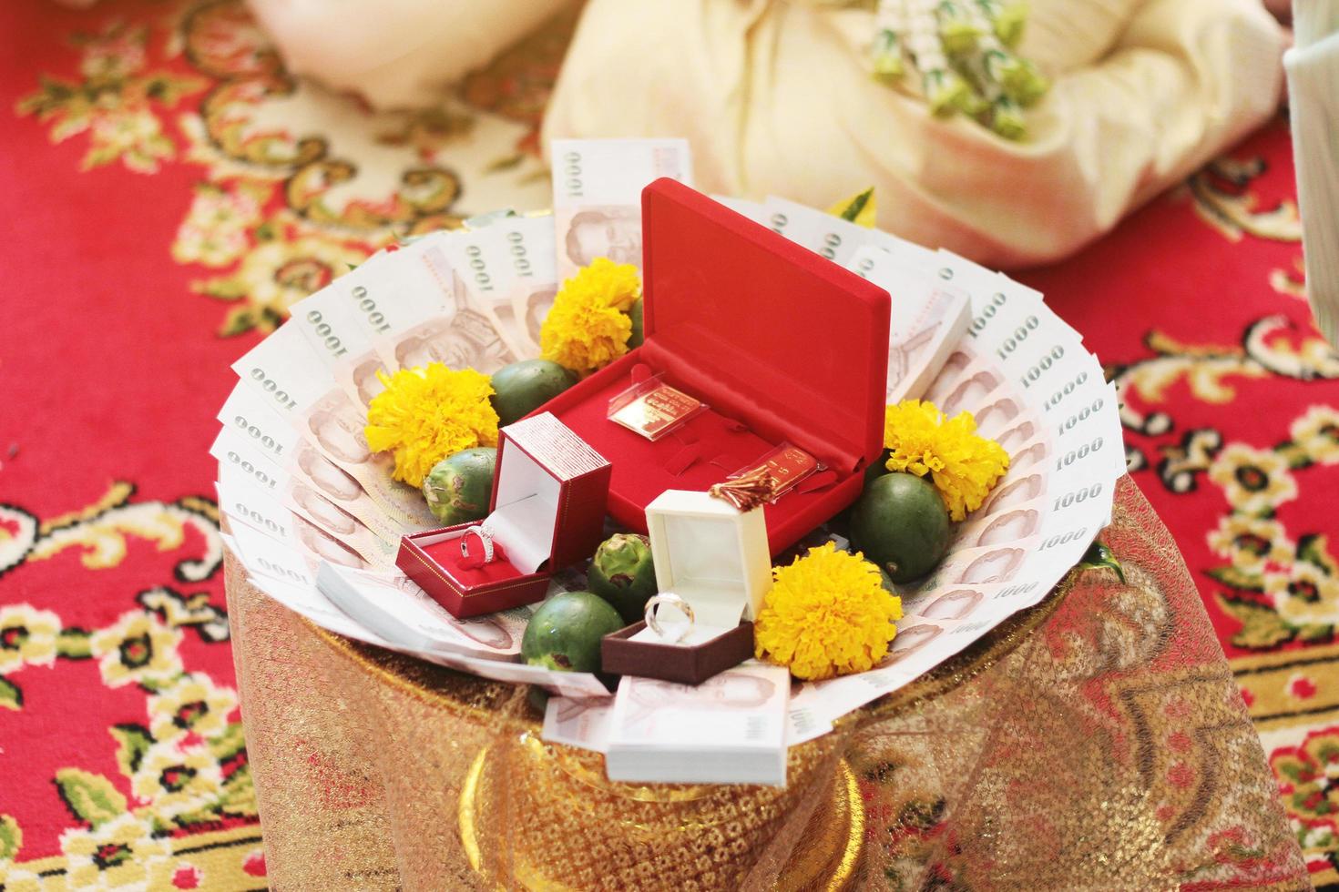 thai sedlar, guld ringar, grön betel nötter och ringblomma blommor på Guldfat för bröllop ceremoni i thailand traditionell foto