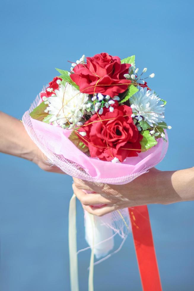 par kärlek hand innehav skön ro blommor bukett. valentine dag och bröllop ceremoni begrepp foto