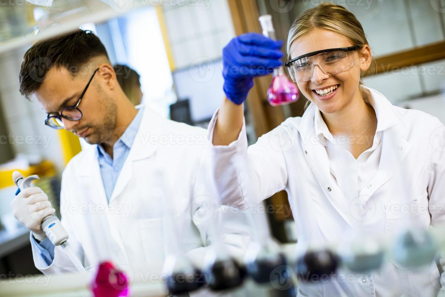 ung kvinnlig forskare som undersöker vätska i biokemiskt laboratorium foto