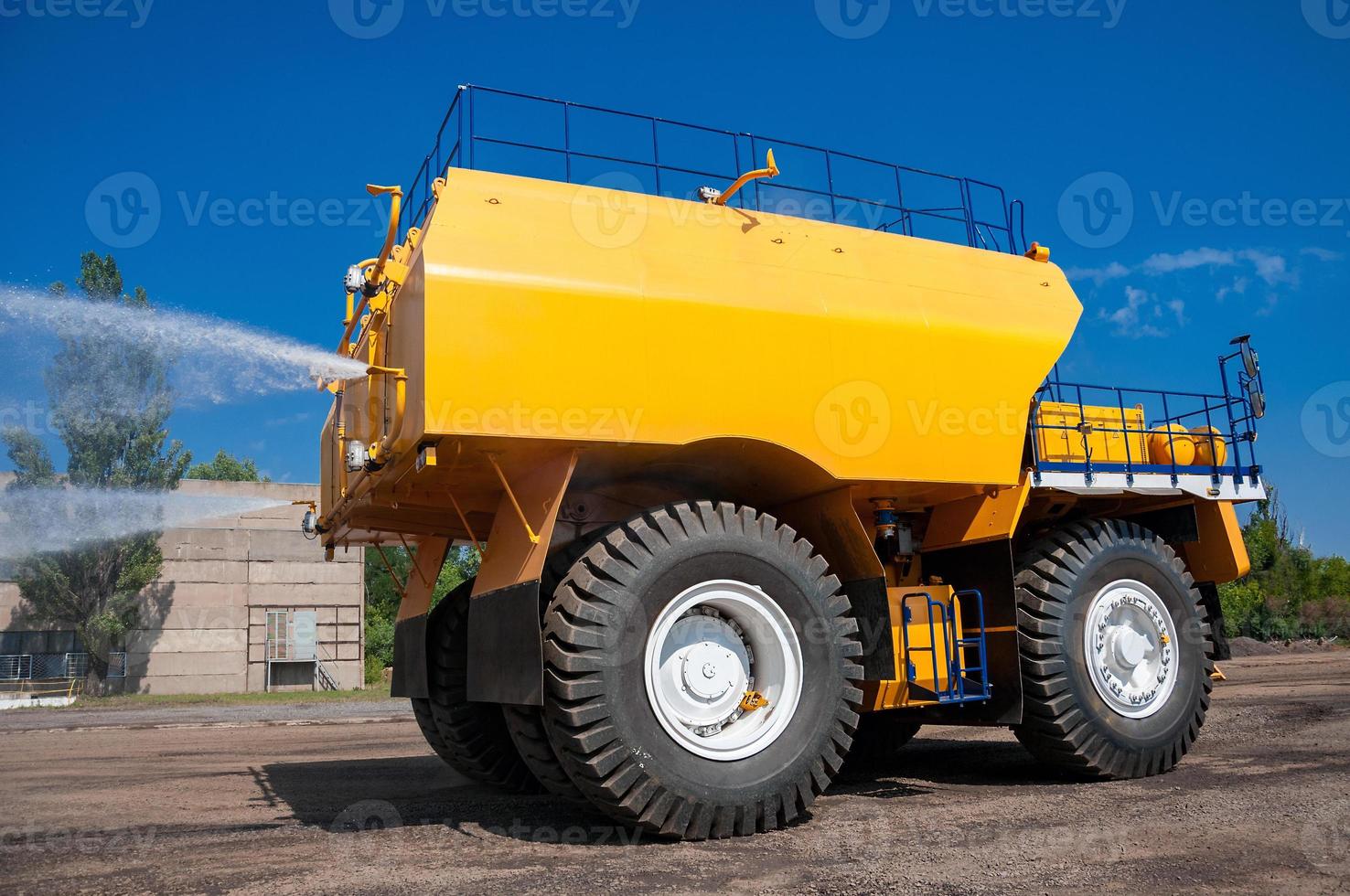 tung gul bevattnar maskin vattning industriell område på solig molnfri dag foto