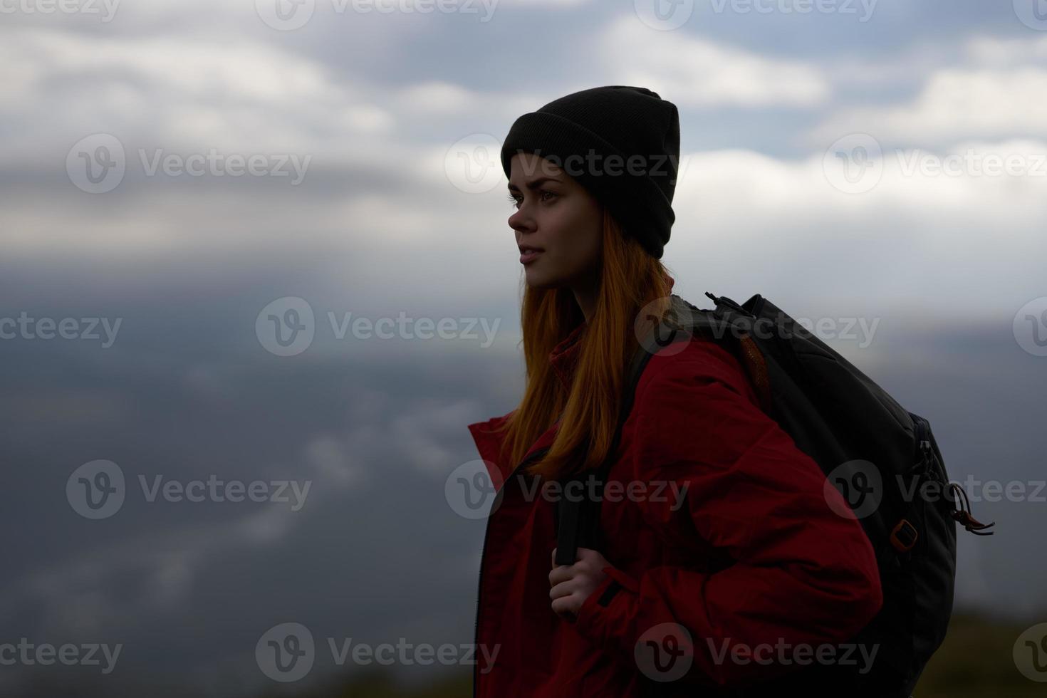 kvinna resor i de bergen med en ryggsäck i de kväll landskap moln väder foto