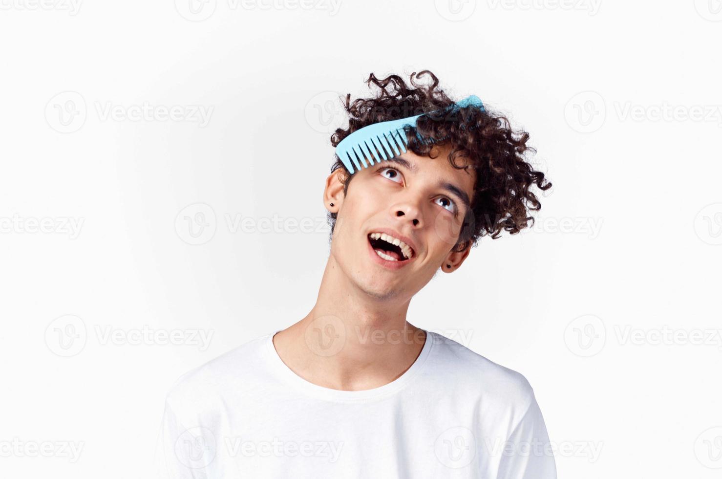 en kille i en vit t-shirt kammar lockigt hår foto