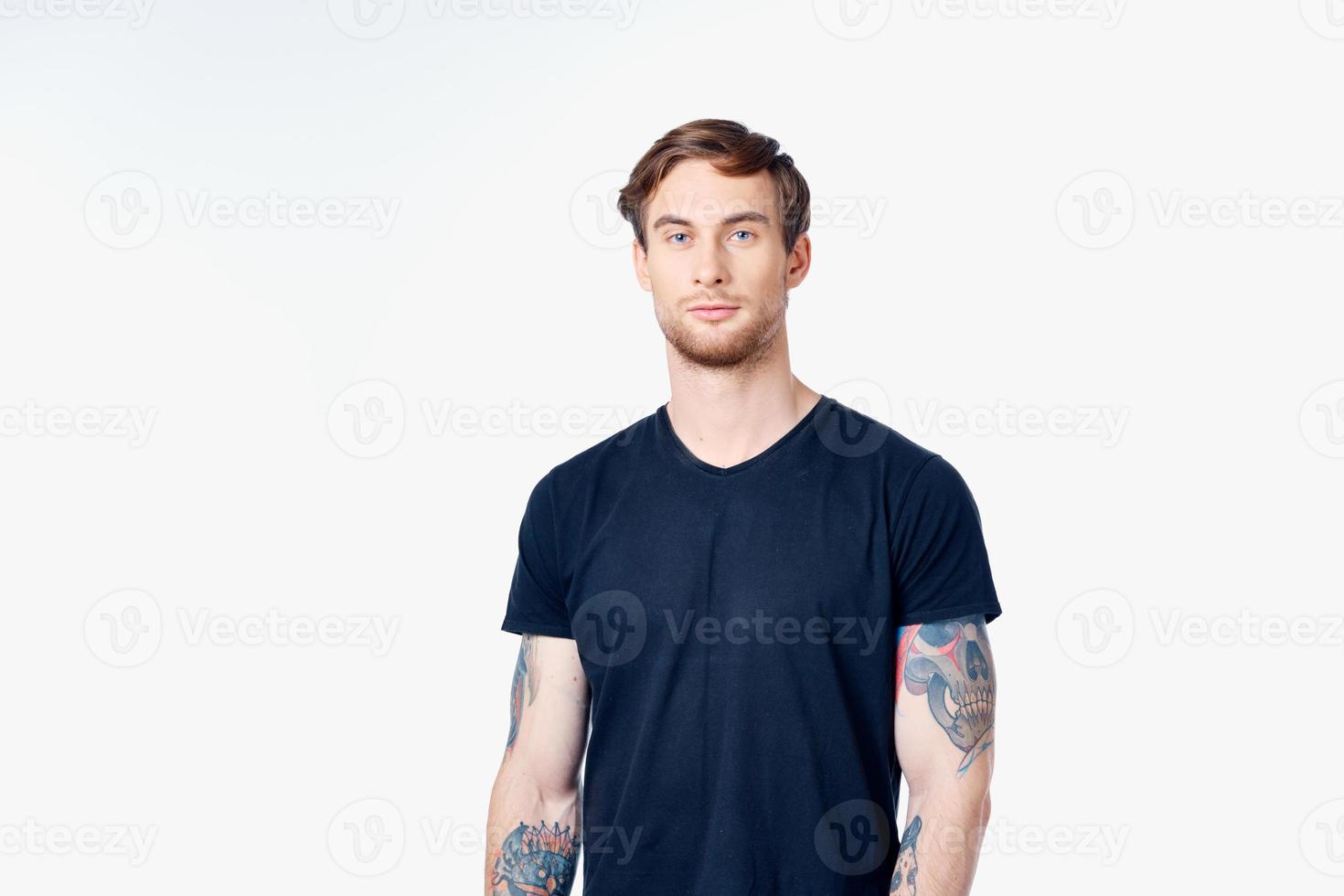 sportig man i en blå t-shirt med tatueringar på hans vapen på en vit bakgrund kopia Plats foto