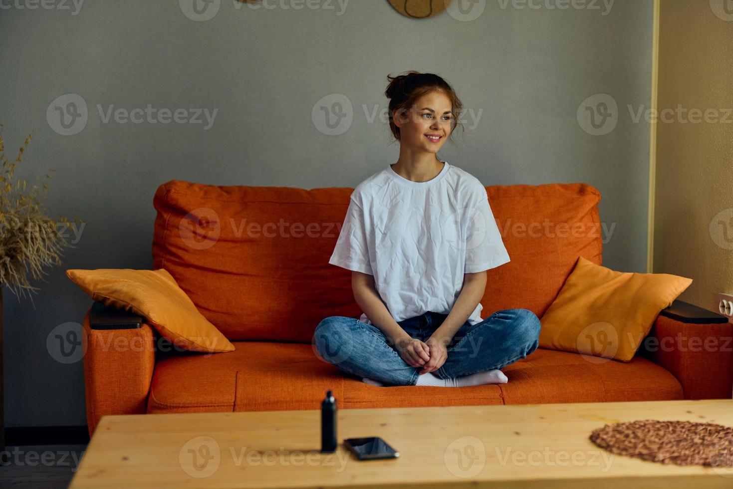 kvinna Sammanträde på de soffa på Hem nära de tabell med en telefon och vape foto