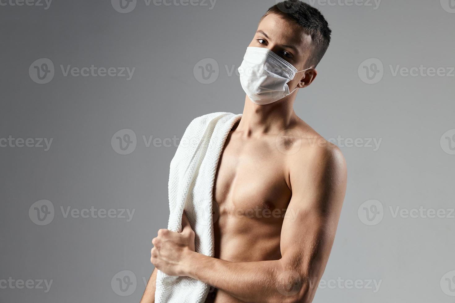 manlig atletisk fysik handduk på axlar medicinsk mask foto