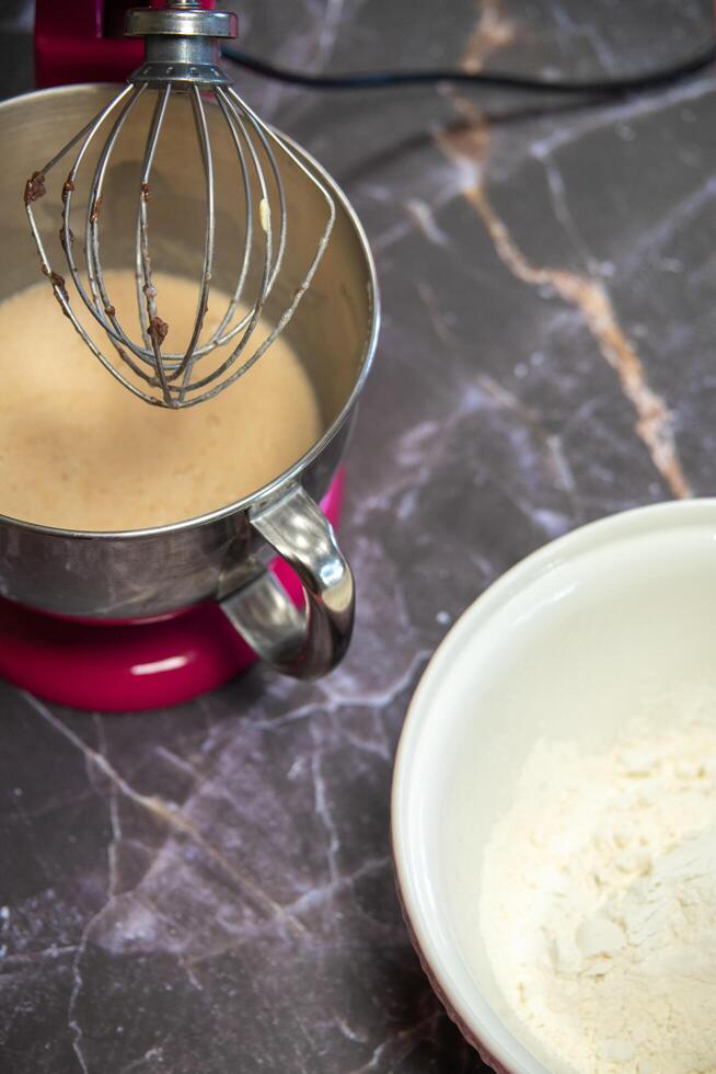 skål med mjöl bredvid en stor mixer på en mörk marmor bakgrund foto