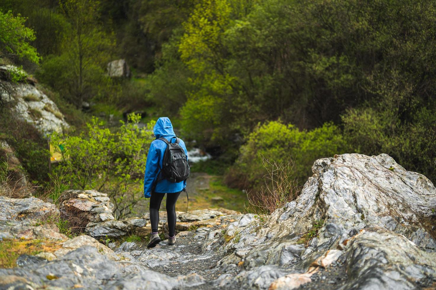 flicka som går på berget medan det regnar med vegetation foto