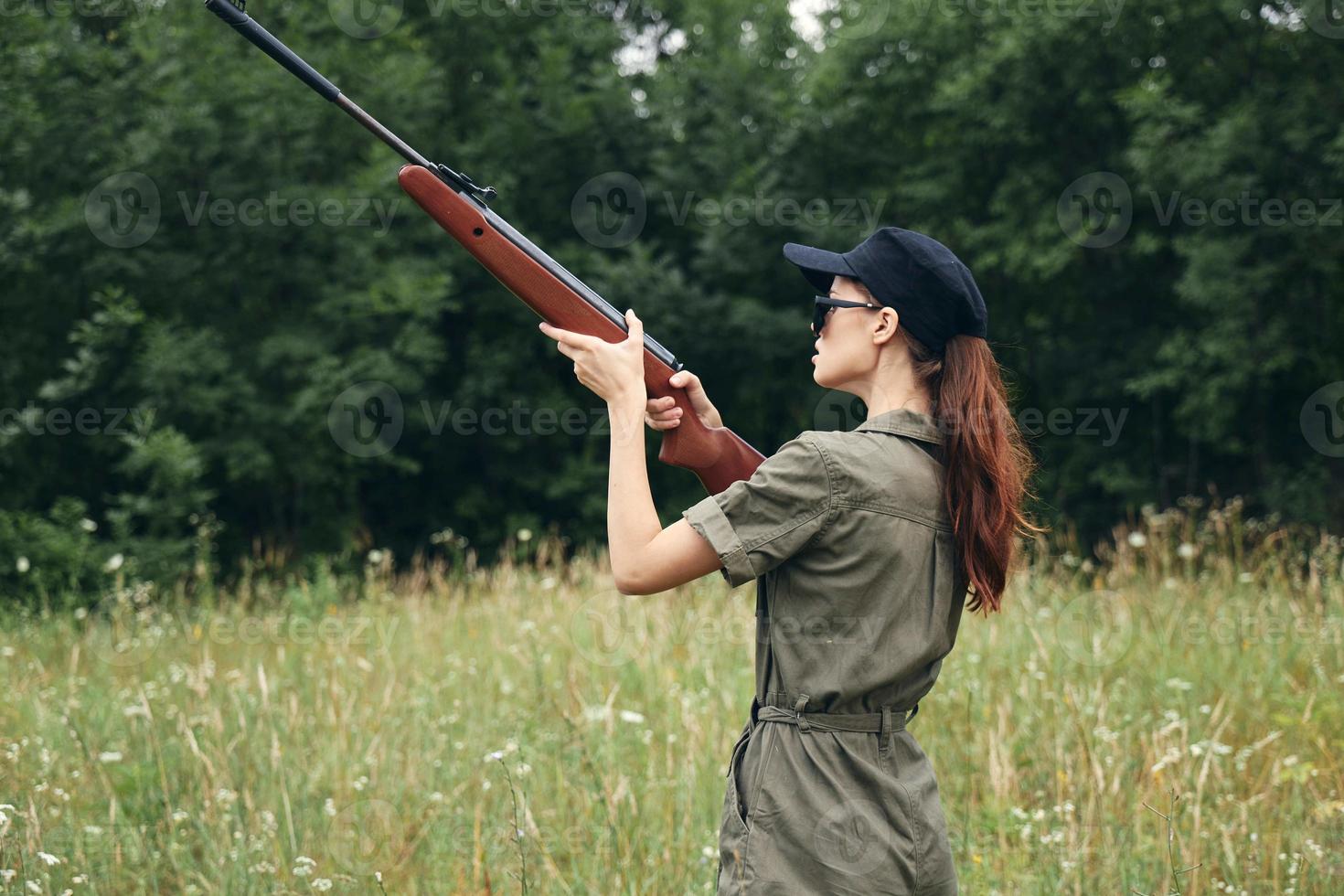kvinna på utomhus- innehar de pistol upp siktar jakt grön overall foto