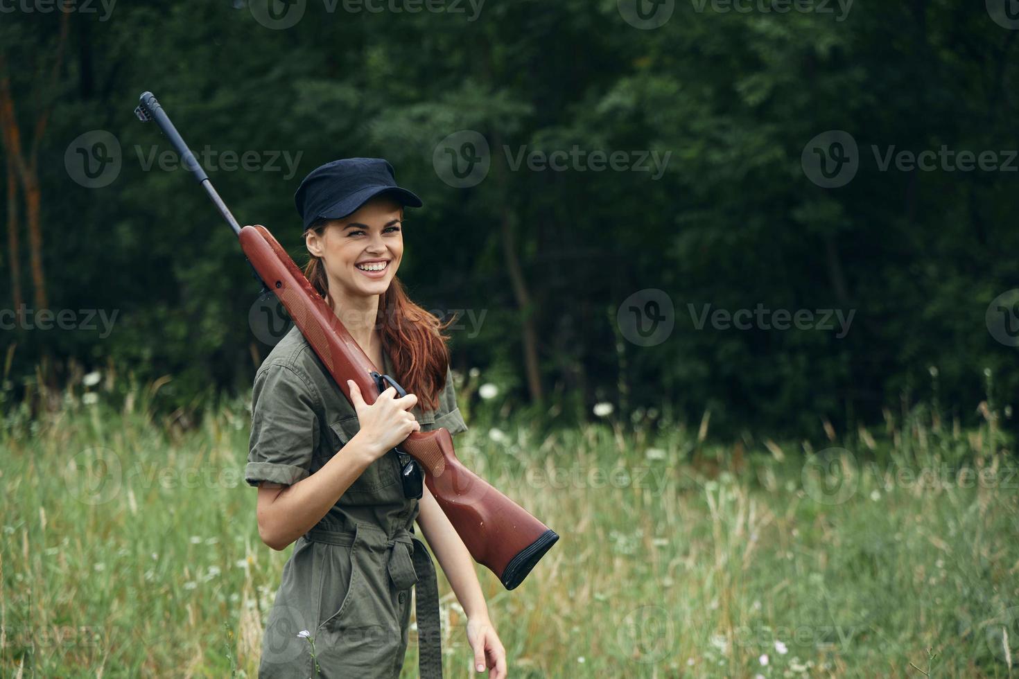 kvinna soldat glad leende hagelgevär på axel av grön resa overall svart keps foto