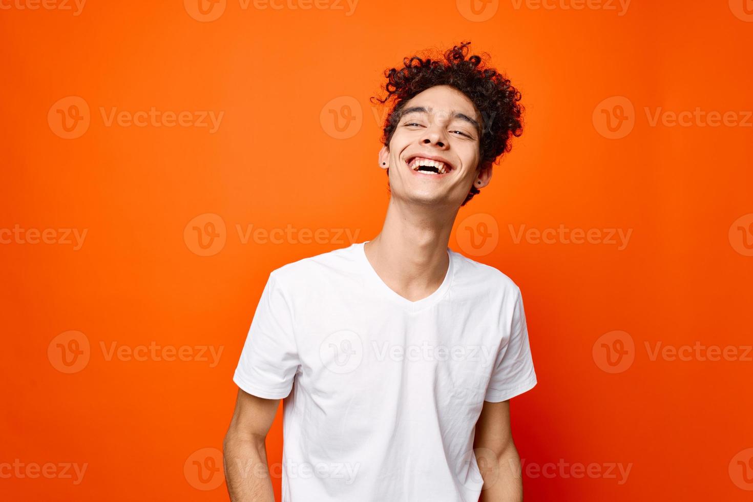 kille i en vit t-shirt gestikulerar med hans hand på ett orange bakgrund foto