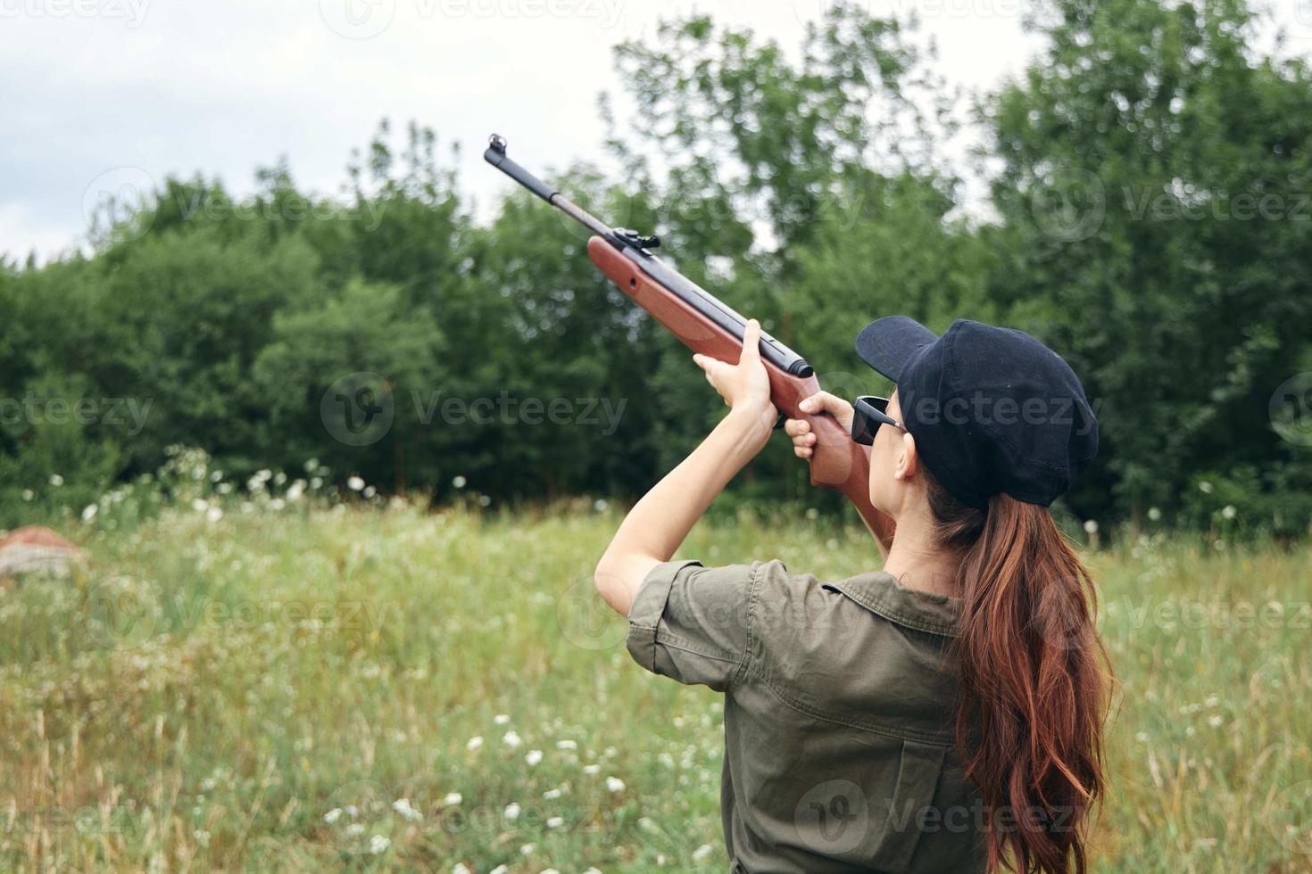 militär kvinna innehav en pistol siktar jakt grön löv foto