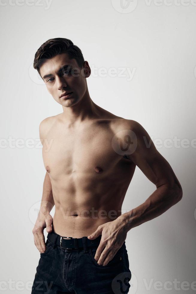 muskulös kille i byxor naken torso beskurna se över grå bakgrund foto