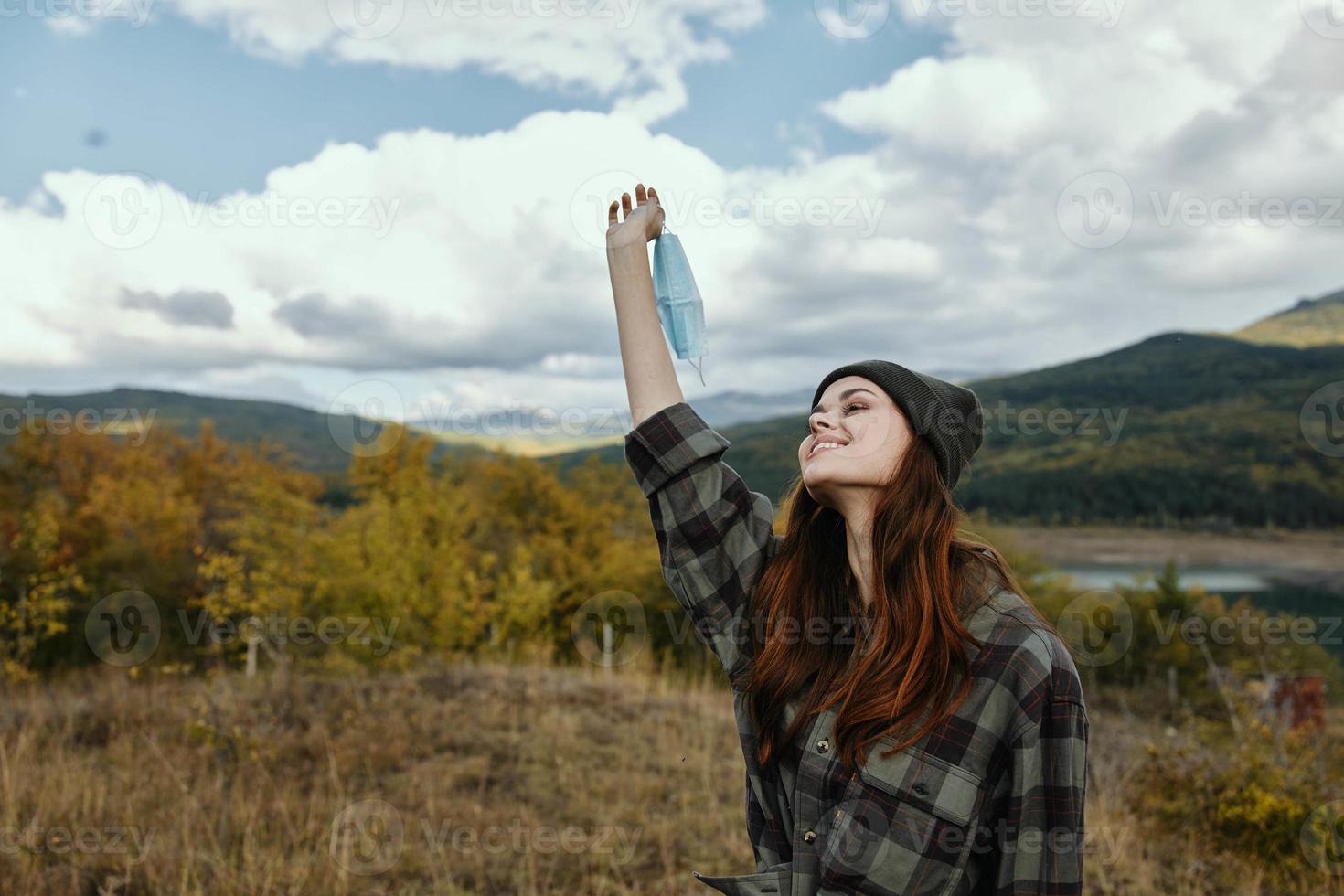 Lycklig kvinna i de bergen Uppfostrad henne hand upp och en medicinsk mask foto