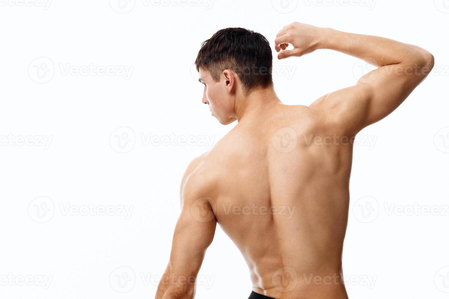 man med atletisk fysik gestikulerar med händer på isolerat bakgrund naken torso tillbaka se foto