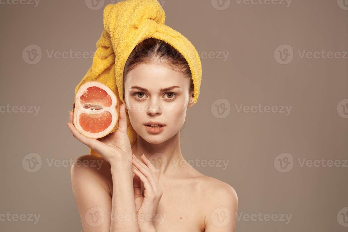 Söt kvinna med handduk på henne huvud rena hud bared axlar citrus- frukt i händer foto