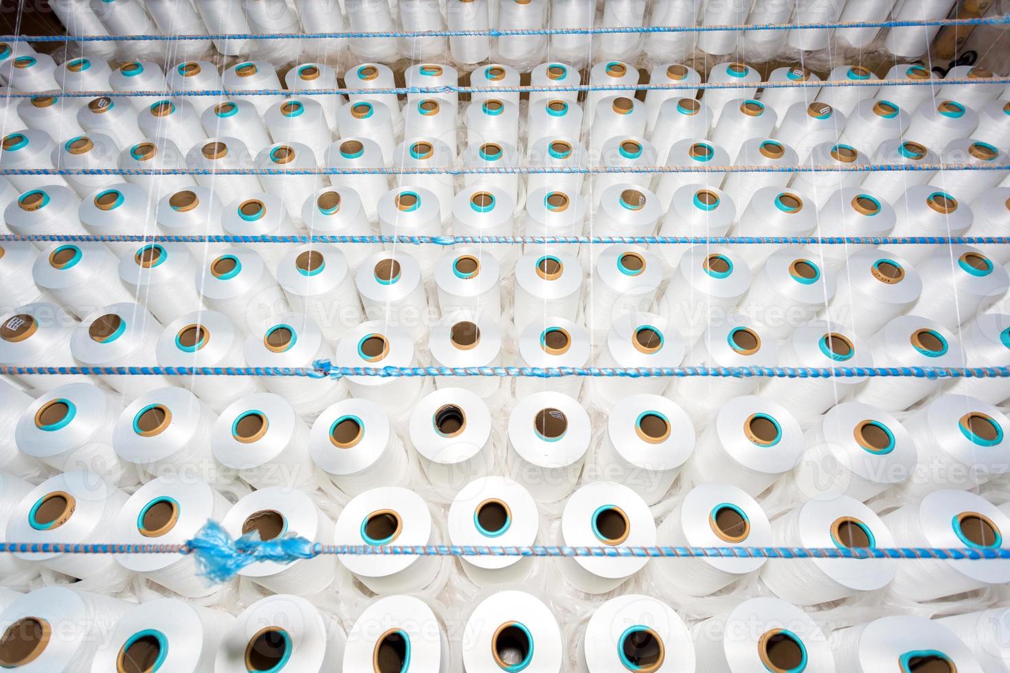 topp se av en massa av vit garn spolar i en textil- fabrik. vit garn spolar i en Kläder fabrik. foto