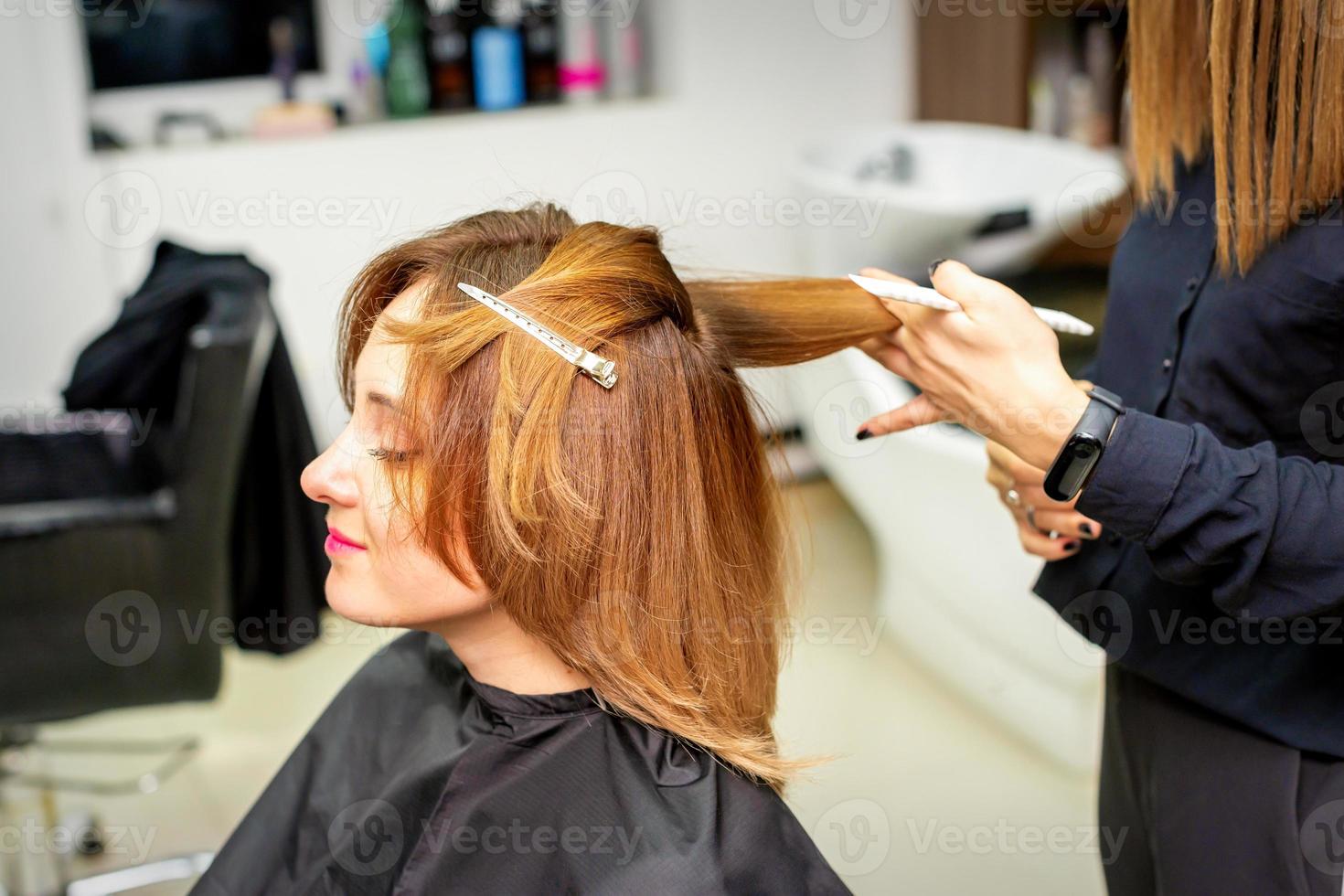 de kvinna klient tar emot en frisyr på de skönhet salong, ung kvinna njuter få en ny frisyr. foto