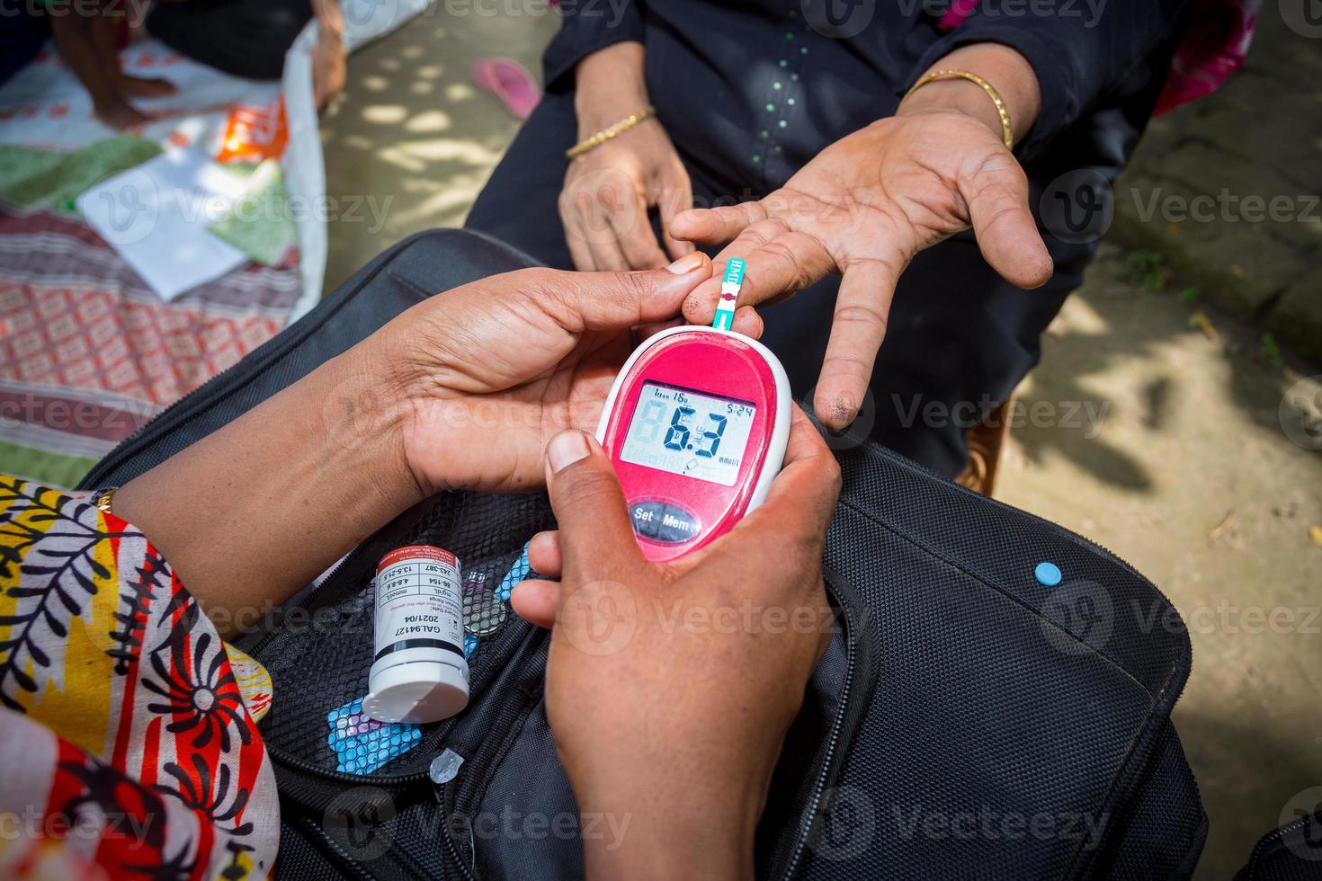 kvinna kontroll socker nivå med glukometer använder sig av en blod prov på narsingdi, bangladesh. lära sig till använda sig av en glukometer. begrepp av diabetes behandling. foto