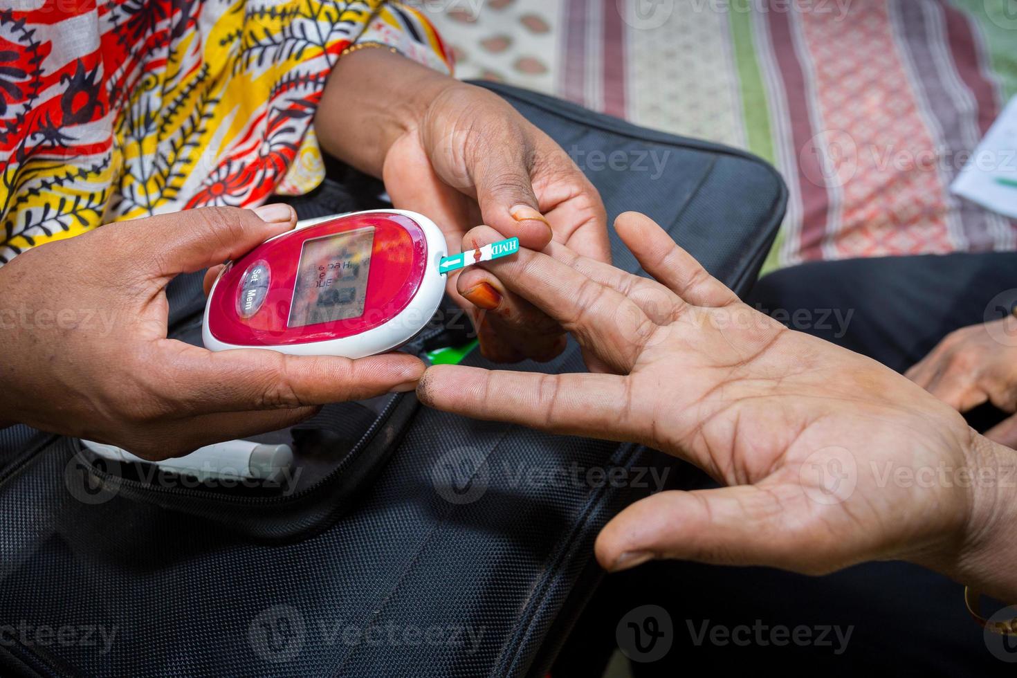 kvinna kontroll socker nivå med glukometer använder sig av en blod prov på narsingdi, bangladesh. lära sig till använda sig av en glukometer. begrepp av diabetes behandling. foto