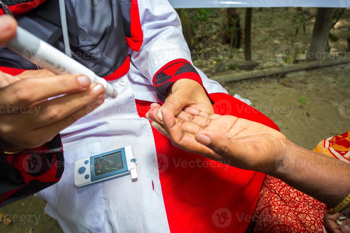 kvinna kontroll socker nivå med glukometer använder sig av en blod prov på narsingdi, bangladesh. lära sig till använda sig av en glukometer. begrepp av diabetes behandling. foto