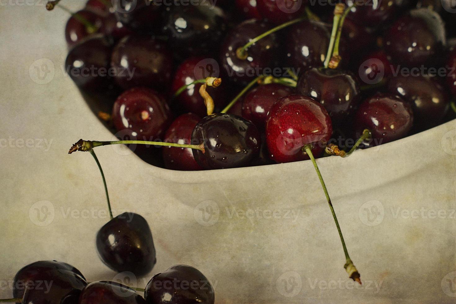 l saftig färsk sommar körsbär i en vit skål på en vintage bakgrund foto