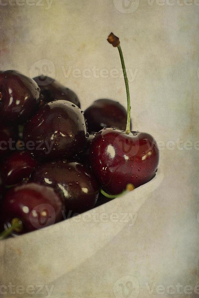 l saftig färsk sommar körsbär i en vit skål på en vintage bakgrund foto